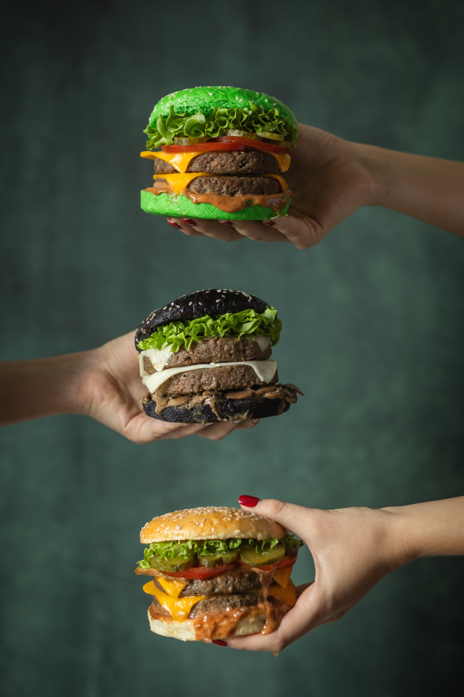 Hands holding colorful vegan burgers